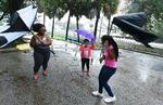 Janesse Brown (tv.) og hendes 12-årige datter Briana Johnson kæmper med blæsten, mens lillesøster Kyra på otte ser til. Billedet er taget i Jacksonville i Florida søndag.  