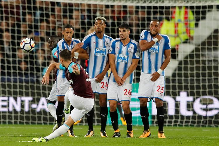 Huddersfields Mathias 'Zanka' Jørgensen (th.) ser ikke ud til at nyde denne situation på London Stadium mandag aften, hvor West Hams Aaron Cresswell hamrer et frispark mod mål. Bolden strøg dog forbi mål.
    
   