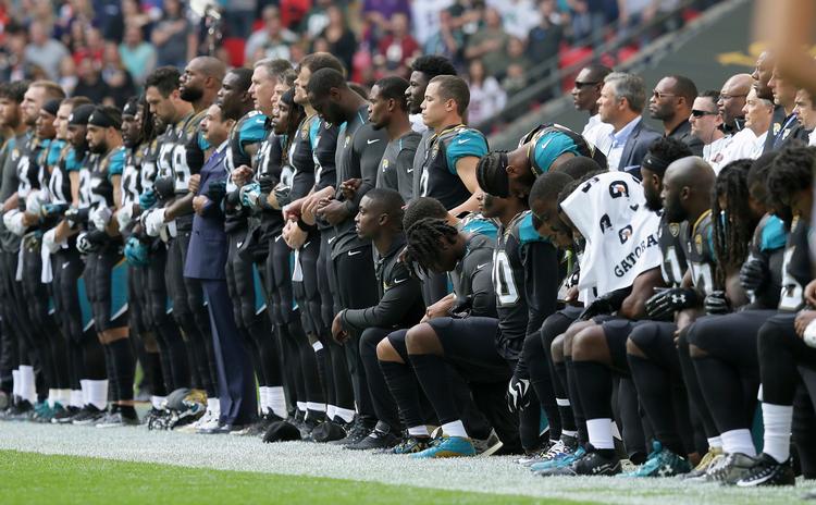 Før en kamp mod Baltimore Ravens i London i dag stod spillere og holdets ejer arm i arm eller knælede.  