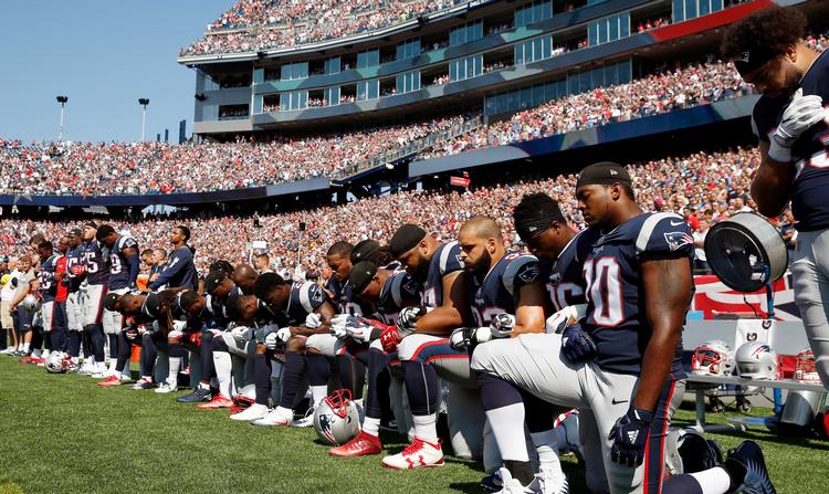 Over 200 spillere protesterede i weekenden mod Donald Trump. Her er det spillere fra New England Patriots, der knæler under nationalsangen før en kamp i NFL mod Houston Texans. 