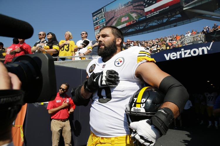 Her står Alejandro Villanueva fra Pittsburgh Steelers alene lige akkurat uden for spillertunnelen, og dermed er hans gestus under nationalsangen synlig for publikum. Få meter bag ham står hans holdkammerater, som er skjult for publikum. De kan anes i nederste højre hjørne af billedet. 