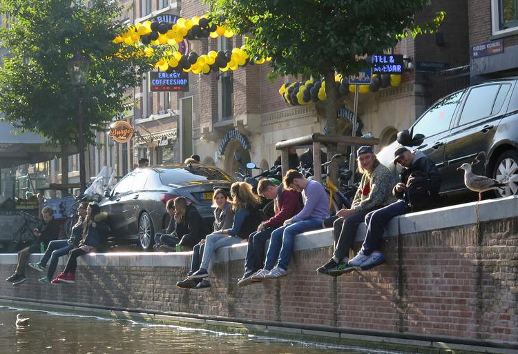 Turister og lokale slapper af ved kanalen i Amsterdams centrum. Mens nogle lokale er trætte af turisterne, har de besøgende generelt set et rigtig godt indtryk af Amsterdam og dets indbyggere. 