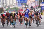 Fernando Gaviria passerer målstregen som vinder af sidste etape i Tour of Guangxi og har overskud til at signalere, at det var hans fjerde sejr i løbet. Magnus Cort, der blev nr. 5, er næsten skjult helt ude til venstre af rytteren med rød hjelm italieneren Andrea Guardini, der besatte fjerdepladsen. Foto: Tim De Waele.
 