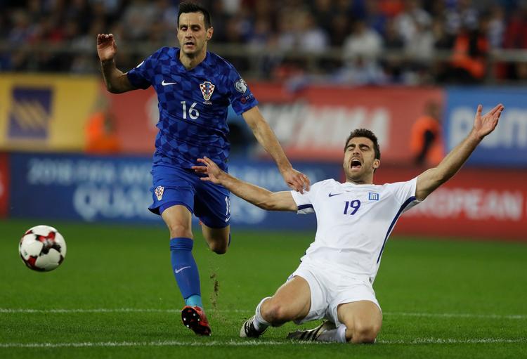Grækenlands Sokratis Papastathopoulos (th.) slår ud med armene i afmagt, mens Kroatiens Nikola Kalinic jagter bolden under søndagens kamp i Piræus.
   