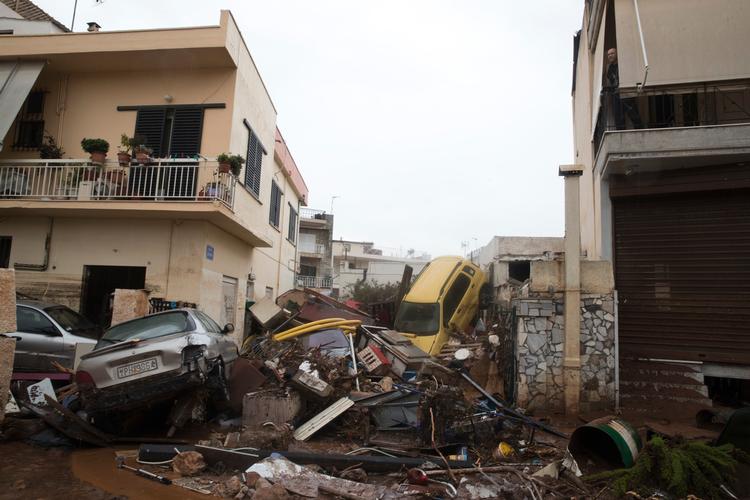 
    A man, top right, looks out from his home over piles of vehicles in the municipality of Madra western Athens, on Wednesday, Nov. 15, 2017. Flash floods in the Greek capital's western outskirts Wednesday turned roads into raging torrents of mud and debris, killing at least nine people, inundating homes and businesses and knocking out a section of a highway. (AP Photo/Petros Giannakouris)
   