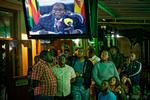 Robert Mugabe har de seneste dage været sat i husarrest af landets militær. Han har netop afsluttet en tale, som alle forventede ville indeholde en aftrædelse fra posten som præsident. Det gjorde den ikke. Her følger folk hans tale på en bar i Harare i Zimbabwe. (AP Photo/Ben Curtis) 
