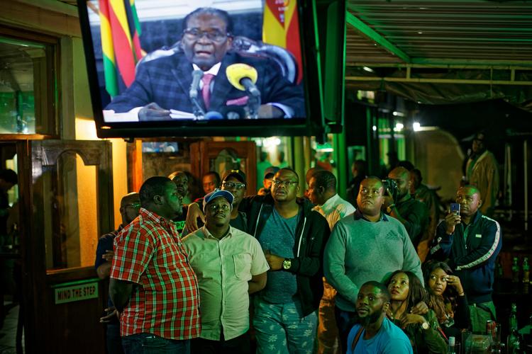 Robert Mugabe har de seneste dage været sat i husarrest af landets militær. Han har netop afsluttet en tale, som alle forventede ville indeholde en aftrædelse fra posten som præsident. Det gjorde den ikke. Her følger folk hans tale på en bar i Harare i Zimbabwe. (AP Photo/Ben Curtis) 