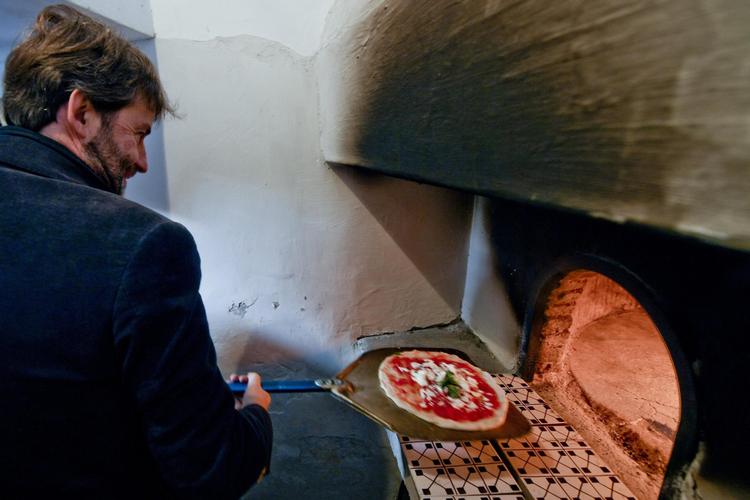 Den italienske kulturminister fejrer udnævnelsen af pizza som kulturarv ved at bage en pizza i verdens angiveligt første pizzaovn i Napoli. Foto: Ciro Fusco/ANSA Via AP
   
