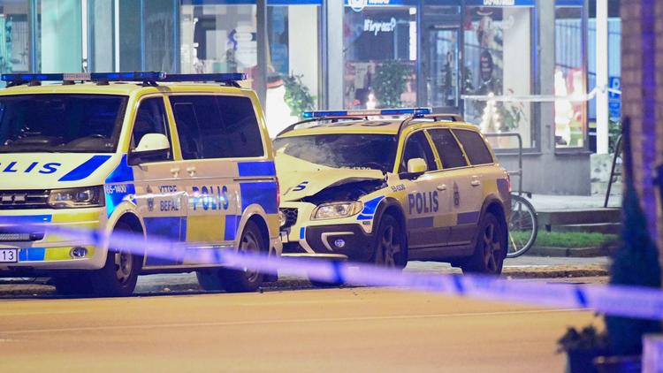 Motorhjelmen og skærmen over det ene forhjul er revet delvist af og krøllet på politibilen i baggrunden ved eksplosionen.  