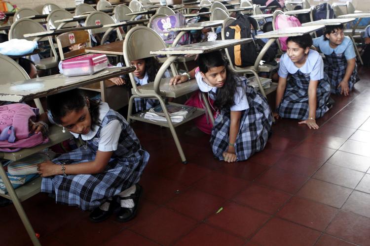 Migranter fra El Salvador har siden jordskælvet i 2001 lovligt kunnet slå sig ned i USA for at bo og arbejde. Billedet er fra 2006, hvor skolebørn i San Salvador øver sig i beskyttelse i anledning af 20 året for jordskælvet i 1986, som dræbte 1.500 mennesker.  