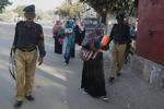 Bevæbnede betjente beskytter sundhedsarbejdere under en vaccinationskampagne i Pakistan. 