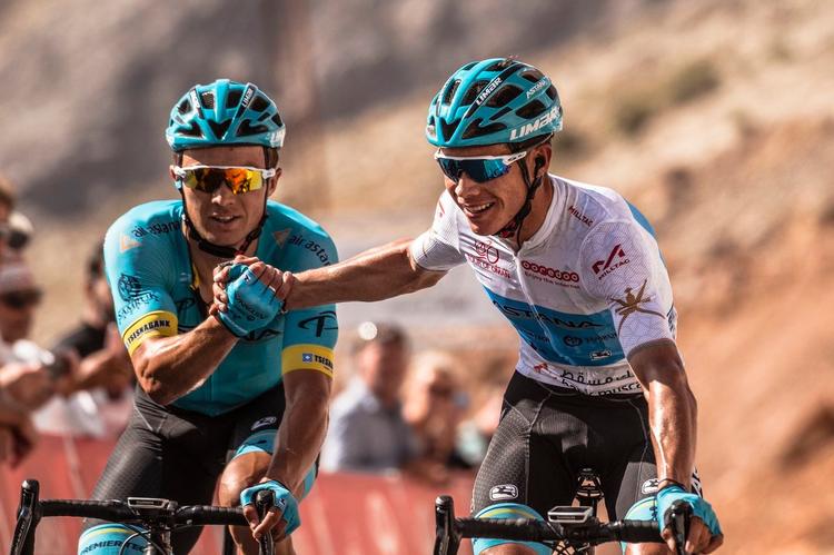 Alexey Lutsenko (t.v.) og Miguel Angel Lopez i løbets ungdomstrøje lykønsker hinanden efter succesen på kongeetapen i Tour of Oman. 