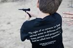 Amerikansk dreng lærer at skyde med pistol i byen Rifle, Colorado. På ryggen bærer han et uddrag af forfatningen. 