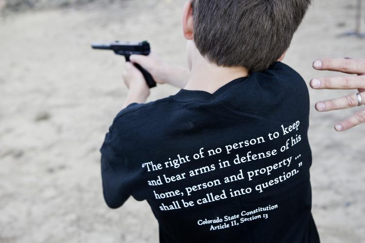 Amerikansk dreng lærer at skyde med pistol i byen Rifle, Colorado. På ryggen bærer han et uddrag af forfatningen. 