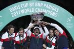 Det franske tennislandshold med holdkaptajn Yannick Noah i midten, iført trofæ, fester efter finalesejren sidste år over Belgien.
    Christophe Ena/AP