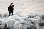 En kvinde går på en mole i Geneve, Schweiz, hvor bølger fra søen har lavet flotte isformationer. Salvatore Di Nolfi/AP