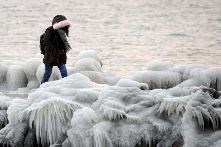 En kvinde går på en mole i Geneve, Schweiz, hvor bølger fra søen har lavet flotte isformationer. Salvatore Di Nolfi/AP