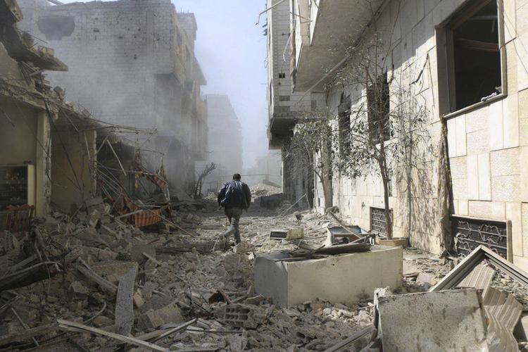 En mand løber af sted gennem et sønderskudt område i det østlige Ghouta. Billedet er offentliggjort af aktivistiske regeringsmodstandere fra Ghouta Media Center. 
   Uncredited/AP
