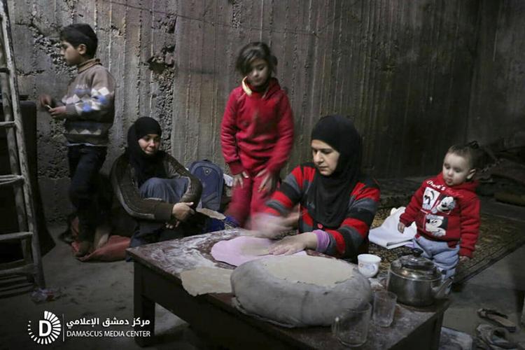 En kvinde bager brød til sin familie, mens kampene ruller videre udenfor. Tusinder af indbyggere i østghouta befinder sig det meste af tiden i kældre og tunnelsystemer under jorden. Billedet er offentliggjort af aktivistiske regeringsmodstandere fra Damaskus Medie Center. 
    
   /AP