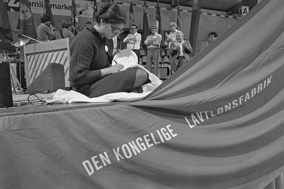 Porcelænsarbejdere strejkede fra Den Kgl. Porcelænsfabrik i august 1976. Deres parole var »Den kongelige lavtlønsfabrik«. Her leger man med fabrikkens navn og laver en modsætning mellem det kongelige og den lave løn. 
   Erik Gleie/POLFOTO