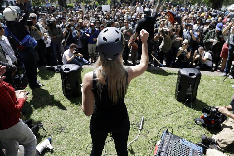 Lauren Southern er kendt for at provokere og vække vrede med sine udsagn og happenings. Ifølge hendes egen forklaring blev hun nægtet indrejse i Storbritannien på grund af uddeling af materiale med teksten 'Allah er homo' under et nyligt besøg i den britiske by Luton. Billedet er fra et arrangement om ytringsfrihed på Berkeley-universitet i Californien, hvor hun har iført sig hjelm som beskyttelse mod kasteskyts. Marcio Jose Sanchez/AP