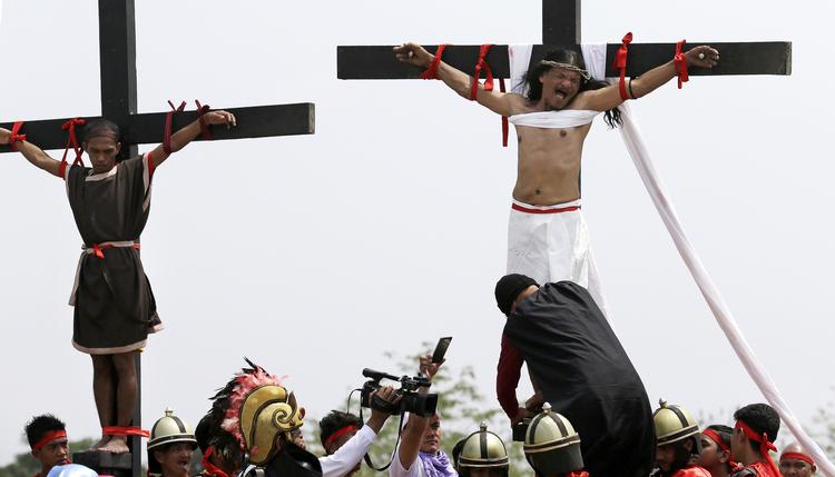 Til højre på billedet hænger Ruben Enaje, som lader sig korsfæste for 32. gang for at opleve Jesus Kristus pinsler.
   Aaron Favila/AP