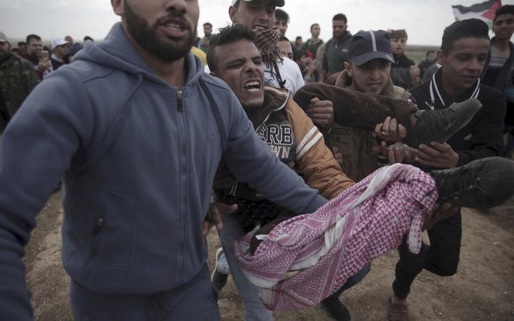 Protesterende palæstinensere bærer en såret mand, der er ramt af israelske soldater.  Khalil Hamra/AP