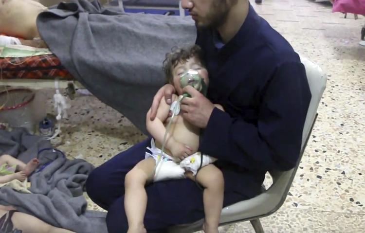 En frivillig holder en iltmaske over et barns ansigt på et hospital, efter et giftgasangreb ramte den syriske by Douma nær hovedstaden, Damaskus, i weekenden. Mindst 42 mennesker døde. /AP