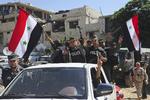 Billede fra det officielle syriske nyhedsbureau, SANA, der viser syrisk politi på vej ind i Douma. SANA/AP