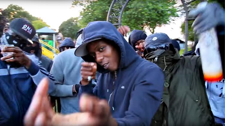 800.00 har set musikvideoen 'M to da N' af Reial 'Lynch' Phillips, som her ses gestikulerende med et fiktivt våben. Han er siden blevet idømt 20 års fængsel, fordi han var med til at skyde 6 personer.   Screendump fra musikvideoen