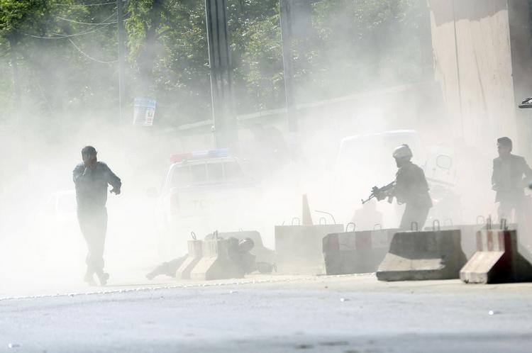 Afghanske sikkerhedsstyrker står ved røgen fra den eksplosion, som selvmordsbomberen udløste.  Massoud Hossaini/AP