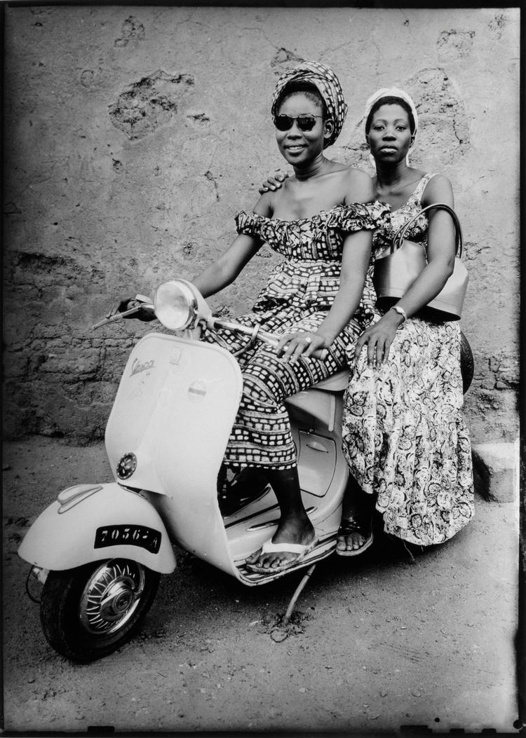 Med lånte solbriller og tasker, sætter to kvinder fra Bamako sig op på en Vespa Scooter. Untitled, 1957 © Seydou Keïta /SKPEAC / courtesy CAAC - The Pigozzi Collection, Geneva