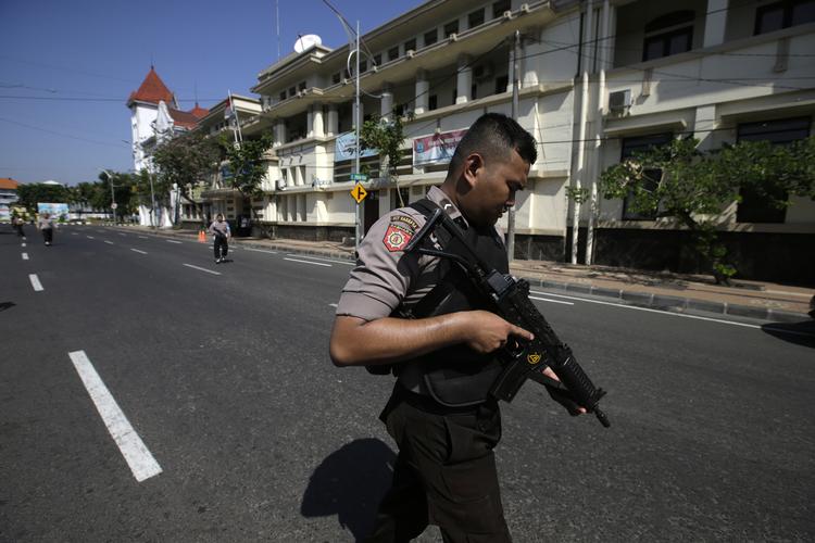 En betjent holder vagt foran politiets hovedkvarter i Indonesiens næststørste by Surabaya. Hovedkvarteret blev mandag morgen udsat for et angreb kun dagen efter, at tre kirker også blev angrebet i byen.
 Achmad Ibrahim/AP