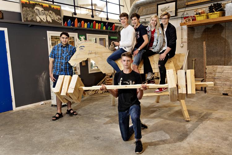 Murad Michael Vural (tv.) fik ideen til den såkaldte torturhest, som 10. klasse-eleverne på 'building and construction'-linjen har lavet sammen på deres faste fredage på værkstedet. Forrest er Thais Glad Christensen, der selv har lavet vægtstangen af træ. Jacob Ehrbahn/POLFOTO