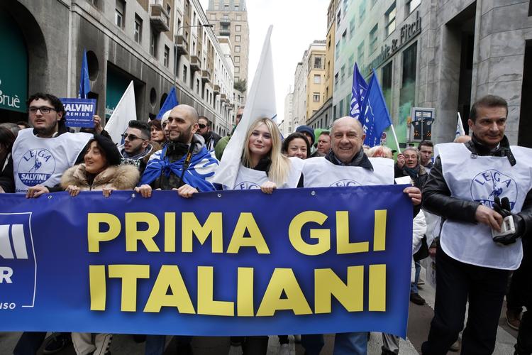 Tilhængere af det højrenationale parti, Ligaen, marcherer under sidste måneds parlamentsvalg med et banner med det Trump-inspirerede budskab 'Italienerne først'. Antonio Calanni/AP