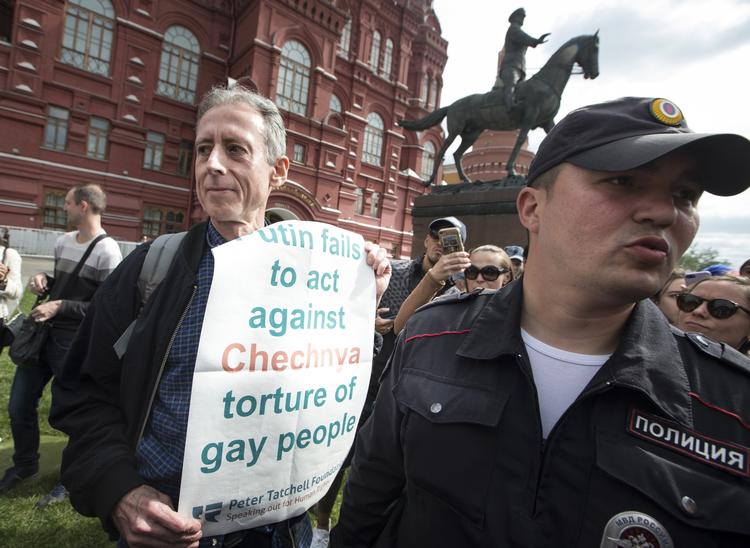 66-årige Peter Tatchell blev ført væk af betjente, efter han havde foldet et banner ud i det centrale Moskva. Alexander Zemlianichenko/AP