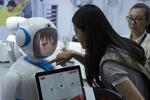 En kvinde ser på en kinesisk fremstillet robot på en teknologiudstilling i Shanghai i forrige uge. Netop robotteknologi ventes at få stor betydning for den globale økonomi i fremtiden. Sam Mcneil/AP