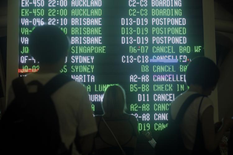 Passagerer tjekker informationstavlen i lufthavnen på Bali.

  Firdia Lisnawati/AP