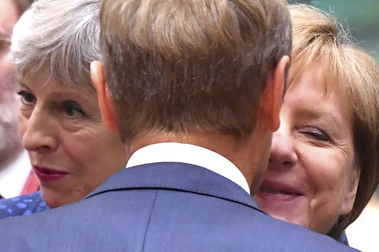 Theresa May og Angela Merkel fotograferet i et gruppekram med EU's præsident, Donald Tusk.  Geert Vanden Wijngaert/AP