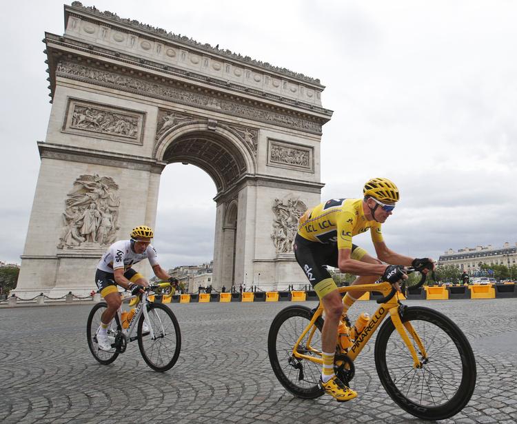 Chris Froome havde sidste år selskab af blandt andre Sergio Henao i sit fjerde sejrrige Tour de France-felttog, men colombianeren, der her ses på hjul af Sky-kaptajnen på Champs-Élysées, er ikke med, når det går løs på lørdag.
   Christophe Ena/AP