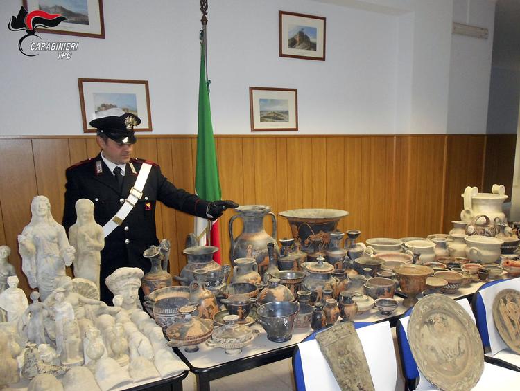En italiensk betjent præsenterer nogle af de beslaglagte genstande. /AP