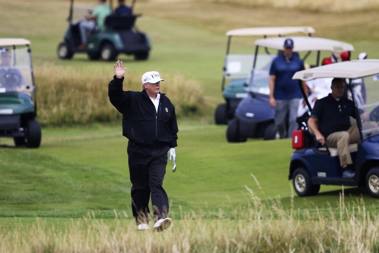 Trump tilbringer weekenden i sit Golf-resort i Skotland, men Putin har travlt med møder med besøgende ledere. Her vinker den amerikanske præsident til demonstranter.
   Peter Morrison/AP