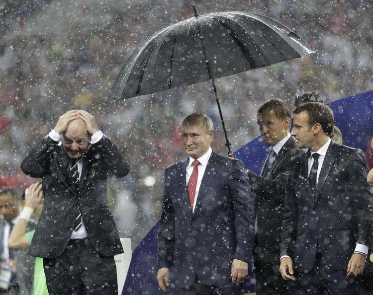 Mens Vladimir Putin hurtigt kom tørvejr, måtte Fifa-præsident Gianni Infantino (tv.) og franske Emmanuel Macron (th.) vente længe på en paraply, da regnen begyndte at stå ned i stænger over Moskva. 
   Matthias Schrader/AP