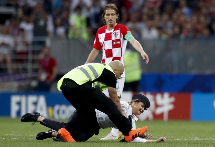 Baneløberne nåede at give high five til flere spillere på banen, inden vagter fik fanget dem og ført dem væk fra banen.    Petr David Josek/AP