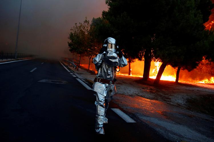 En græsk brandmand i kamp med flammerne i byen Rafina nær Athen. Costas Baltas/Ritzau Scanpix