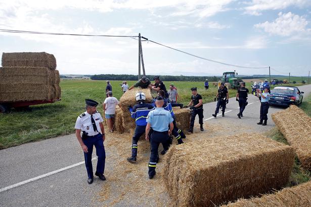 Politiet fjerner halmballer fra vejen, som Tour de France-feltet skulle passere på vejen mod Pyrenæerne.Foto: Reuters/Stephane Mahe  Stephane Mahe/Ritzau Scanpix