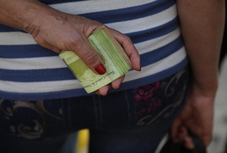 Man skal have mange sedler på sig, når man bevæger sig rundt i Venezuela. Her står en kvinde og gør klar til at betale for en bustur med et ordentligt bundt. Arkivfoto fra februar.
    Ariana Cubillos/AP