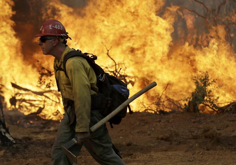 En amerikansk brandmand går langs en fremadstormende naturbrand i byen Redding i Californien, USA, lørdag.
   Marcio Jose Sanchez/AP
