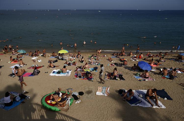 I Barcelona nyder mange strandgæster varmen. Andre har det nok sværere med de høje temperaturer. Manu Fernandez/AP