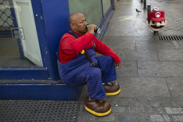 En mand i et Mario-kostume tager en pause på Solpladsen i Madrid, hvor han plejer at posere på turistfotos. Francisco Seco/AP